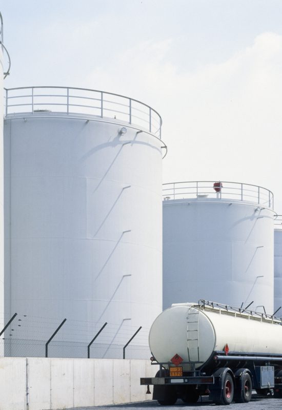 road tanker in front of oil refinery tanks, neutral with copy space